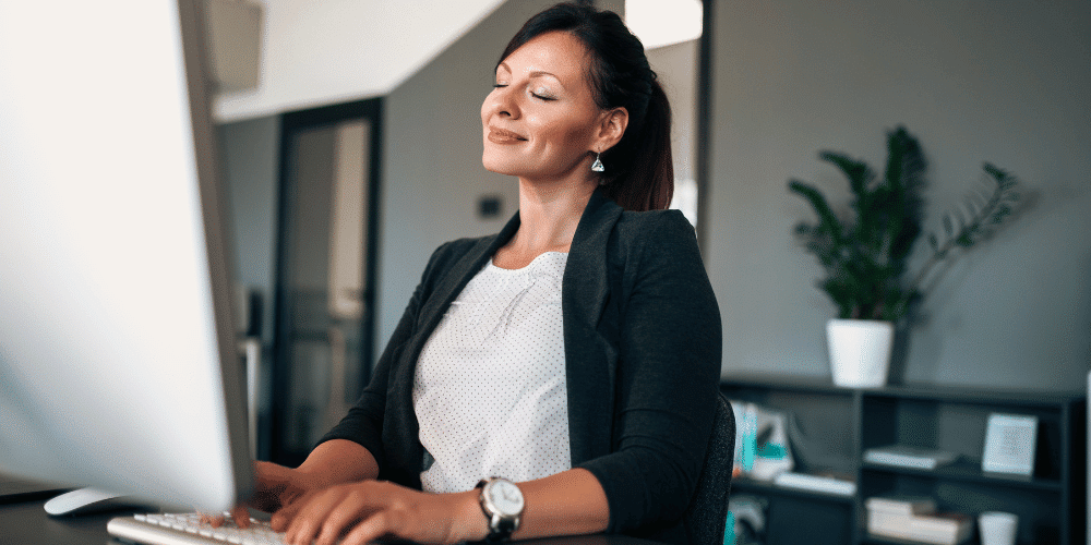 asistente-IA-para-impulsar-la-salud-mental-en-el-trabajo-empleada-feliz-trabajando-servisoftcorp.com